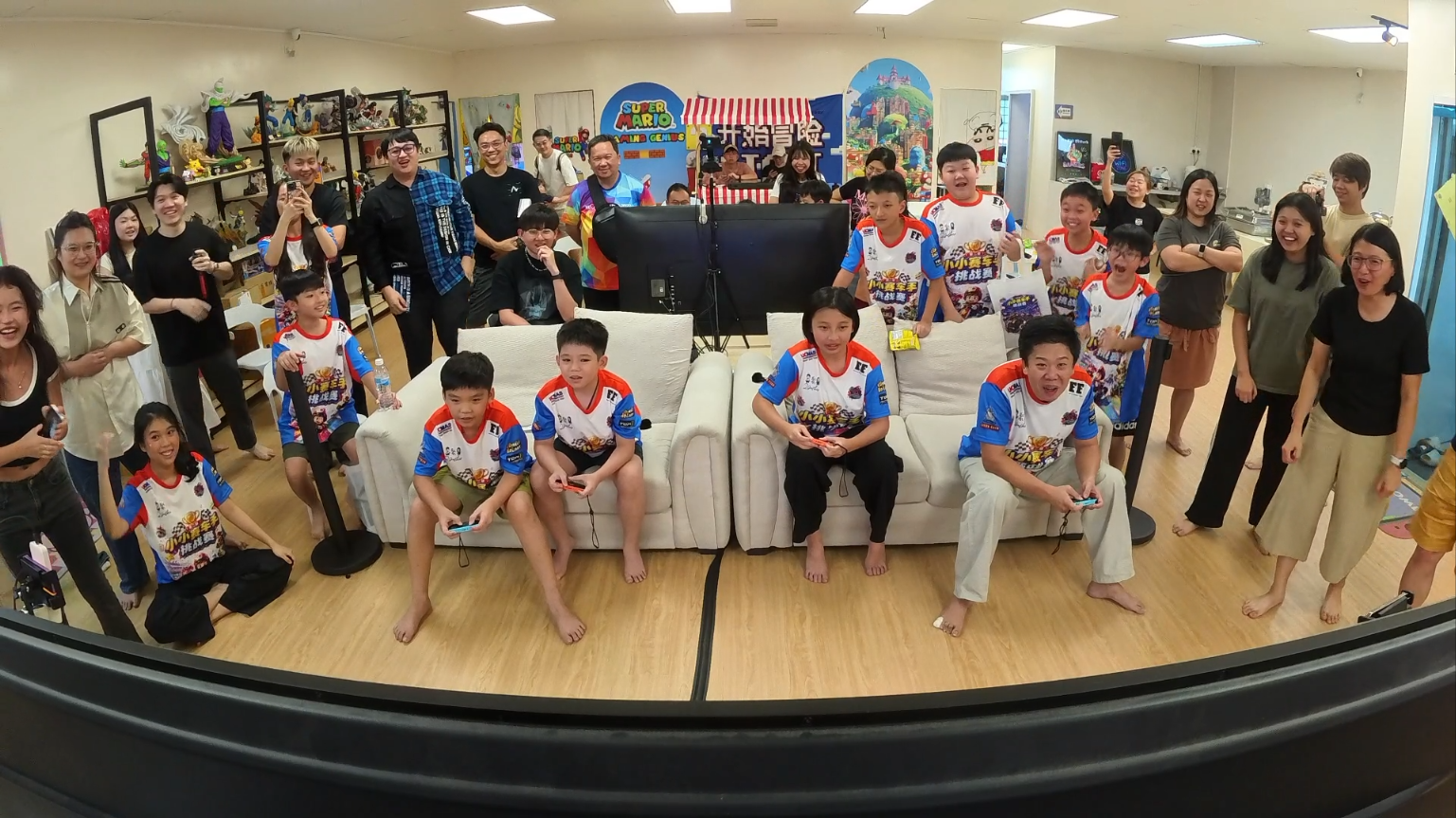 Junior racers playing Nintendo Switch with families cheering at Gaming Genius